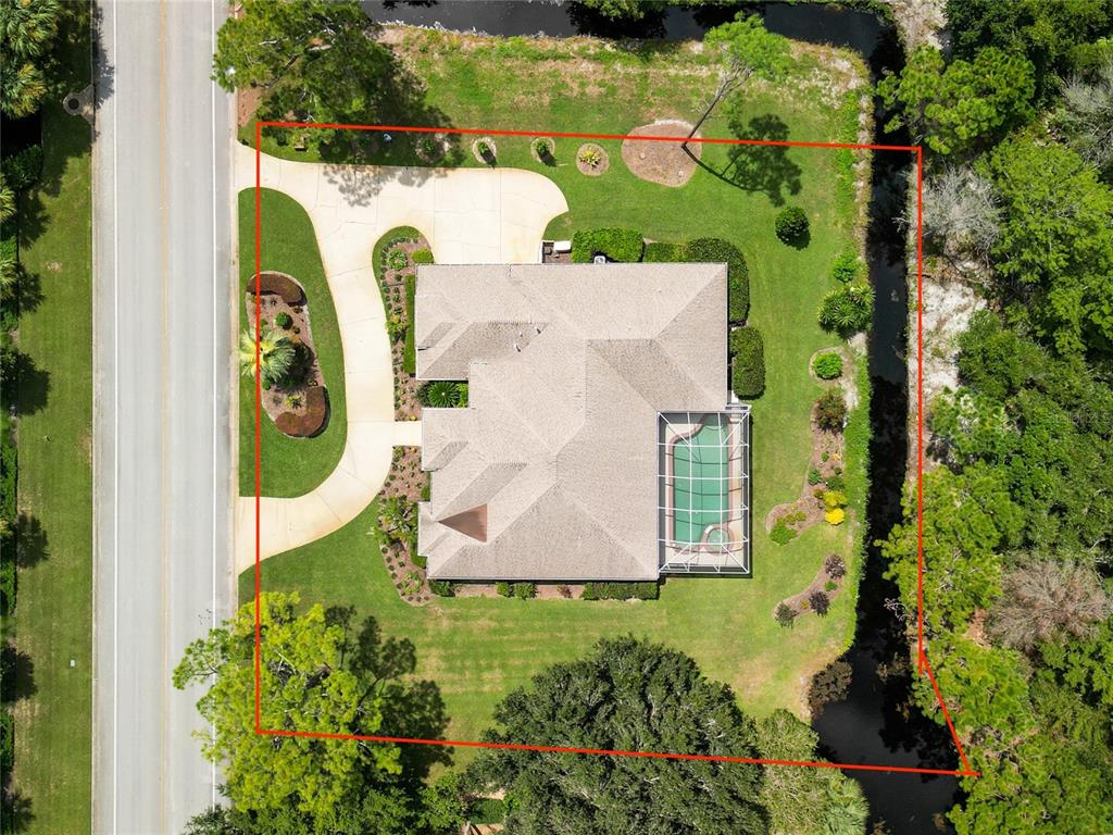 An aerial view shows a house with a pool enclosure on a landscaped residential lot — 1162 CLUB HOUSE BOULEVARD, NEW SMYRNA BEACH, FL