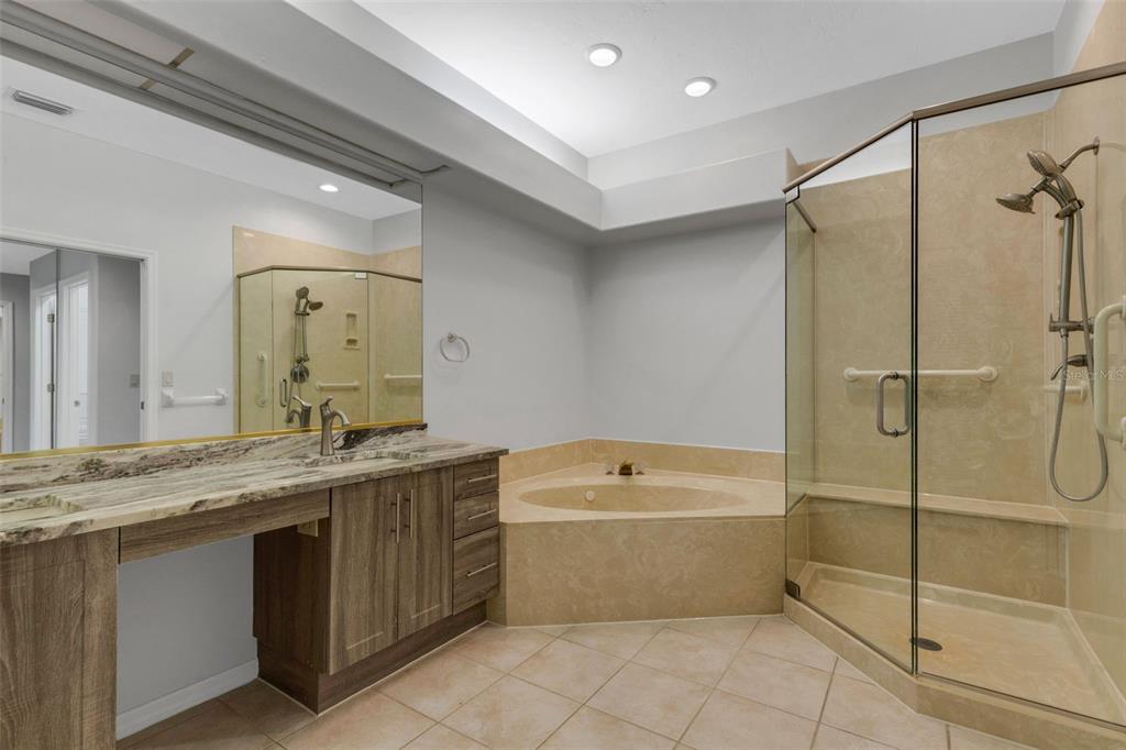 A bathroom features a wood vanity, a corner soaking tub, and a glass-enclosed shower — 4044 PENSHURST PARK, SARASOTA, FL
