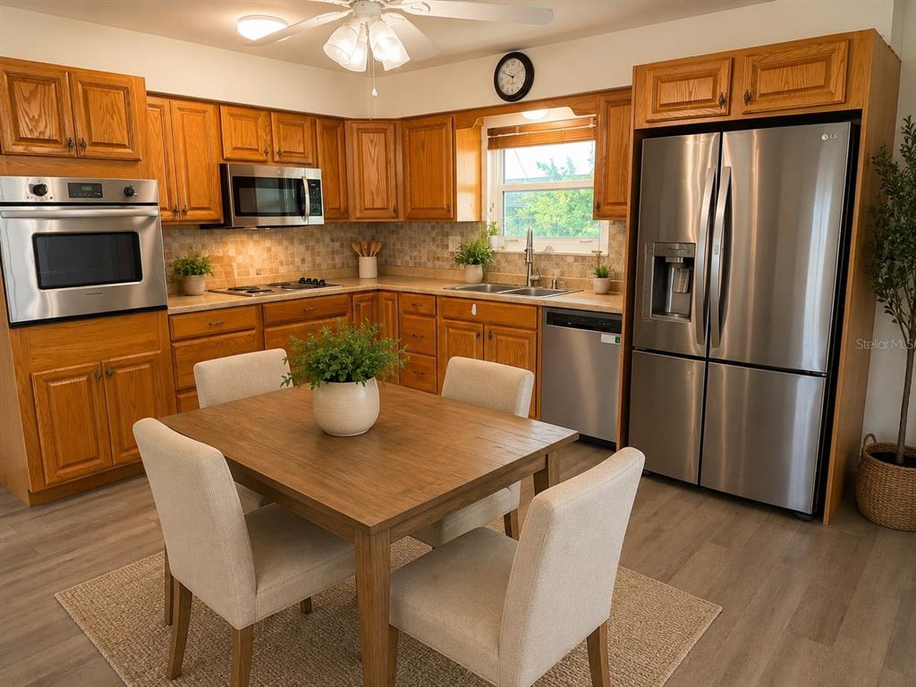 A kitchen features wood cabinets, stainless steel appliances, a dining table, and light-colored flooring — 1505 ARROWHEAD DRIVE, SUN CITY CENTER, FL