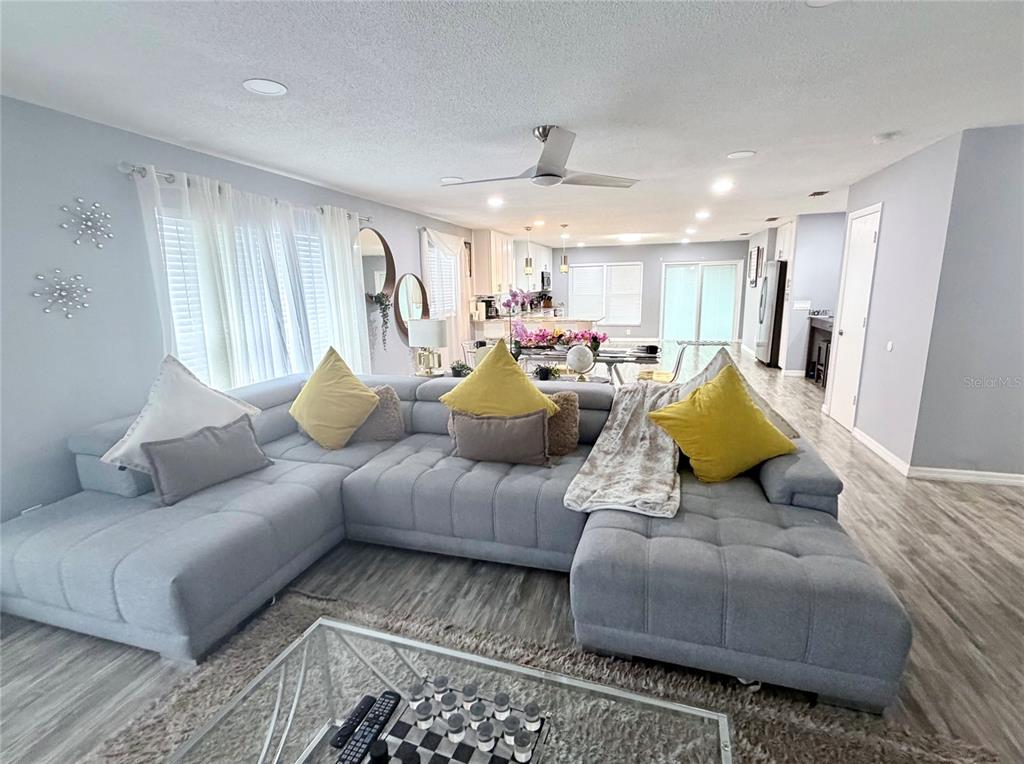 A gray sectional sofa sits on a rug in a living room with light flooring — 4440 BLEASDALE AVENUE, ORLANDO, FL