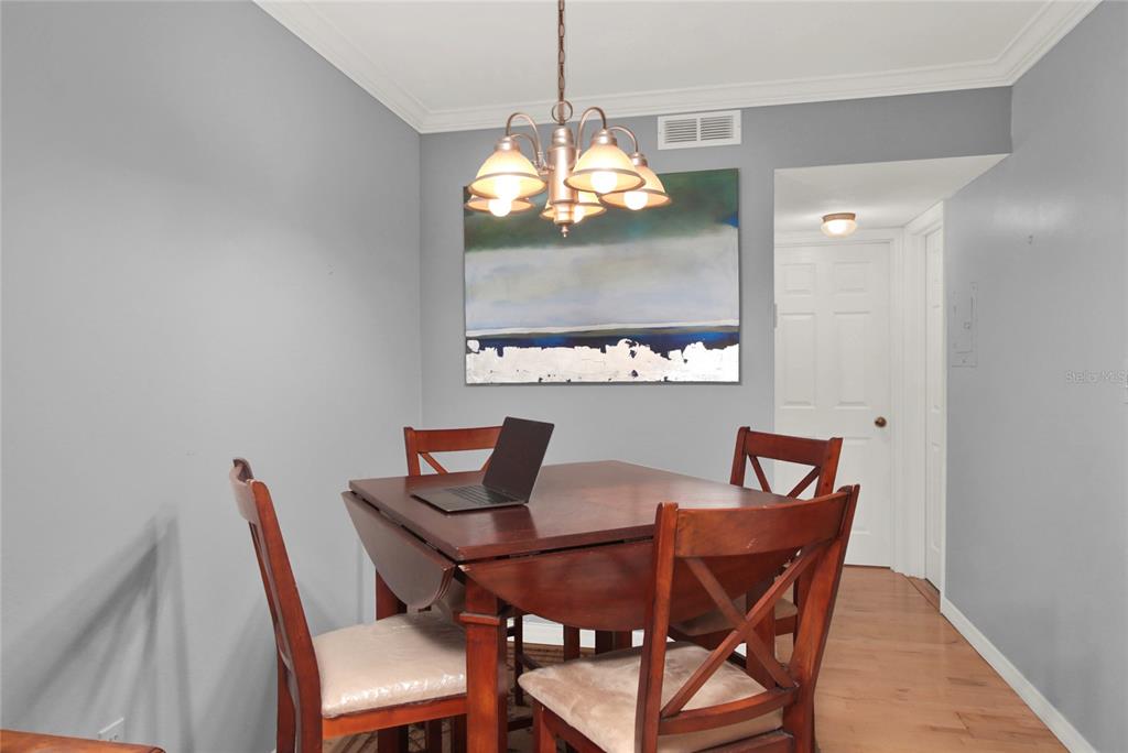A dining room features a wooden drop-leaf table, four chairs, and a hanging light fixture — 2500 LEE RD. UNIT 222, WINTER PARK, FL