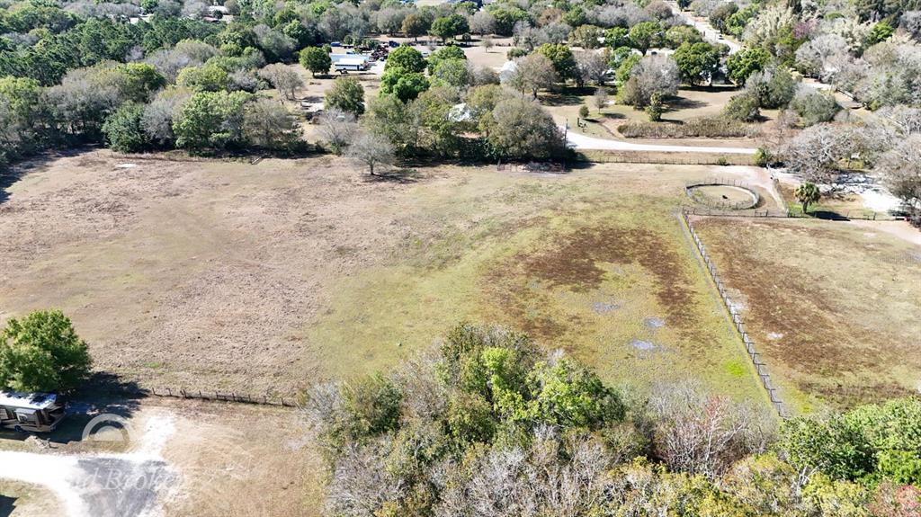 An aerial view shows a large, grassy, fenced-in pasture with scattered trees and a trailer — 448 NW 34TH STREET, OKEECHOBEE, FL