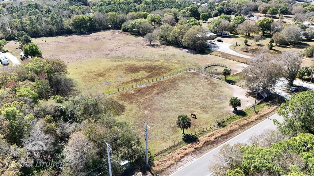 An aerial view shows a fenced pasture with a horse, trees, and a nearby road — 448 NW 34TH STREET, OKEECHOBEE, FL