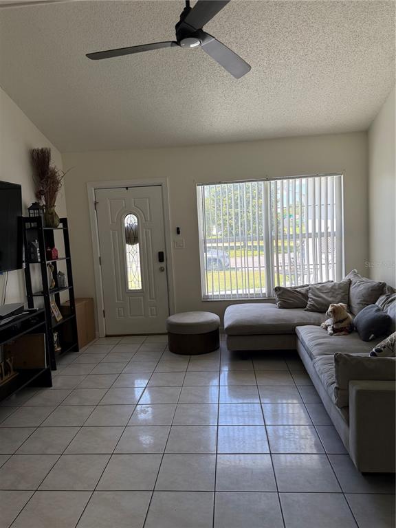 A living room features a white front door, a sectional sofa, and light-colored tile flooring — 217 CITRUS DR, KISSIMMEE, FL