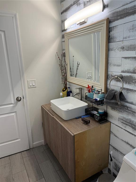 A bathroom features a vessel sink, a wood-toned vanity, and a rustic wood-plank accent wall — 217 CITRUS DR, KISSIMMEE, FL