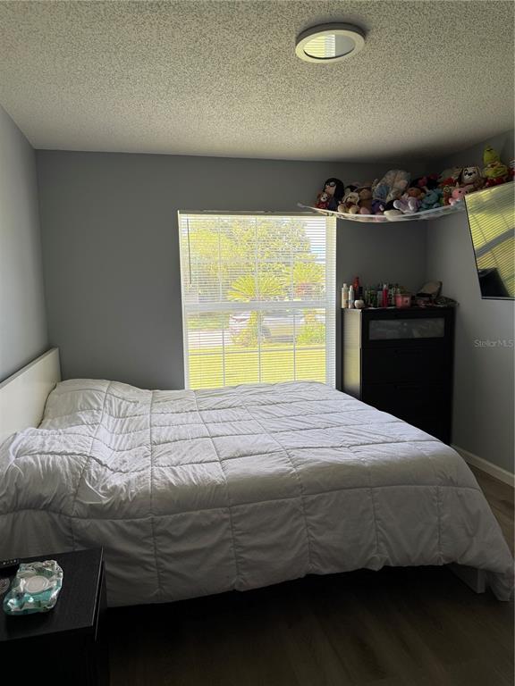 A bedroom features a white bed, a dark dresser, a window, and a corner toy hammock — 217 CITRUS DR, KISSIMMEE, FL