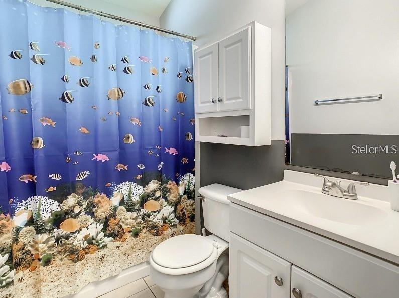 A bathroom features a fish-patterned shower curtain, a white vanity, and a wall-mounted cabinet — 9655 HOLLYHILL DRIVE, ORLANDO, FL