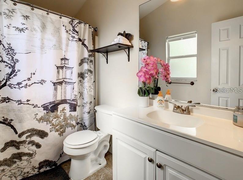 A bathroom features a white vanity, a toilet, and a shower curtain with Asian-inspired art — 9655 HOLLYHILL DRIVE, ORLANDO, FL