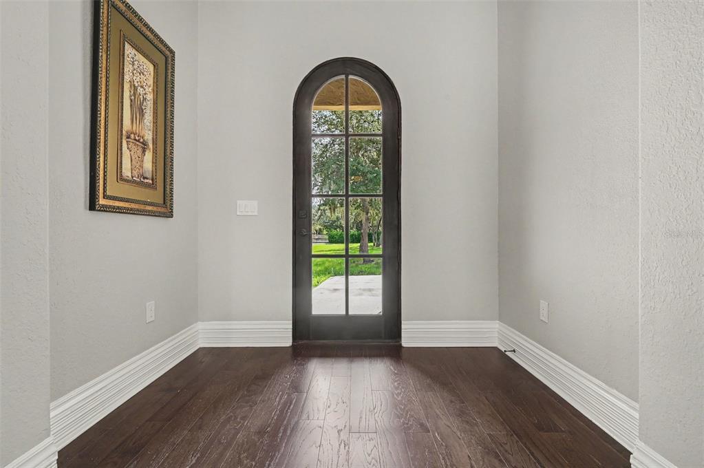 An entryway features dark hardwood floors, light gray walls, and an arched glass-paned door — 2051 LORENE LANE, DELTONA, FL