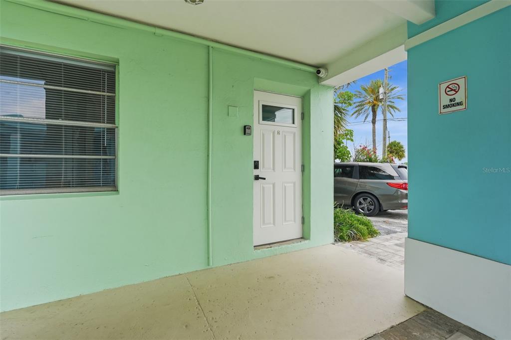 A white door with a keypad lock sits under a covered entryway with pastel walls — 17880 GULF BOULEVARD UNIT 2, REDINGTON SHORES, FL
