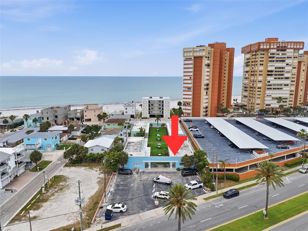 An aerial view shows a light blue building with a courtyard and adjacent parking lot — 17880 GULF BOULEVARD UNIT 2, REDINGTON SHORES, FL