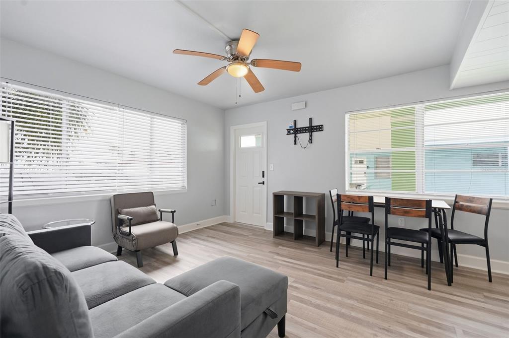 A living and dining area features light wood flooring, a ceiling fan, and large windows — 17880 GULF BOULEVARD UNIT 2, REDINGTON SHORES, FL