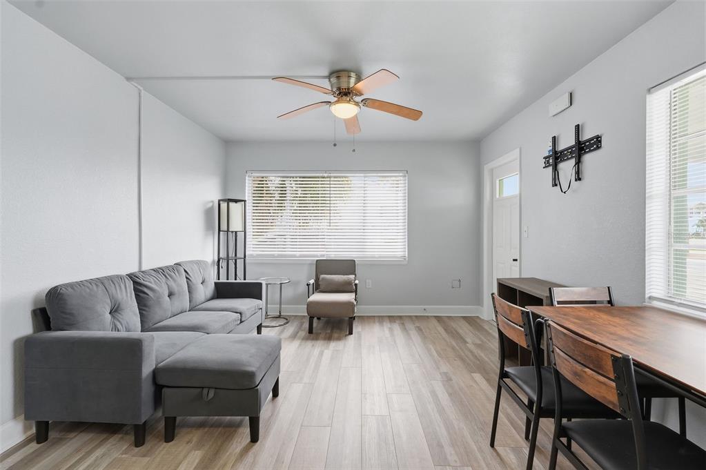 A living room features a gray sectional sofa, a dining table, and light wood flooring — 17880 GULF BOULEVARD UNIT 2, REDINGTON SHORES, FL