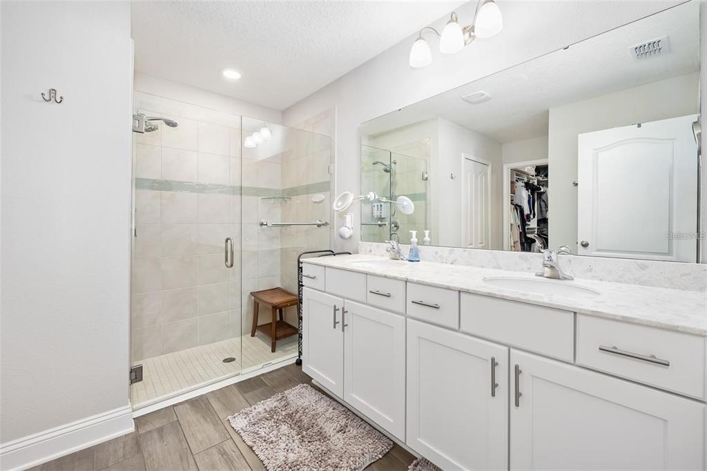 A bathroom features a double vanity with a marble countertop, a walk-in shower, and tile flooring — 64 COASTAL HAMMOCK WAY, ST AUGUSTINE, FL