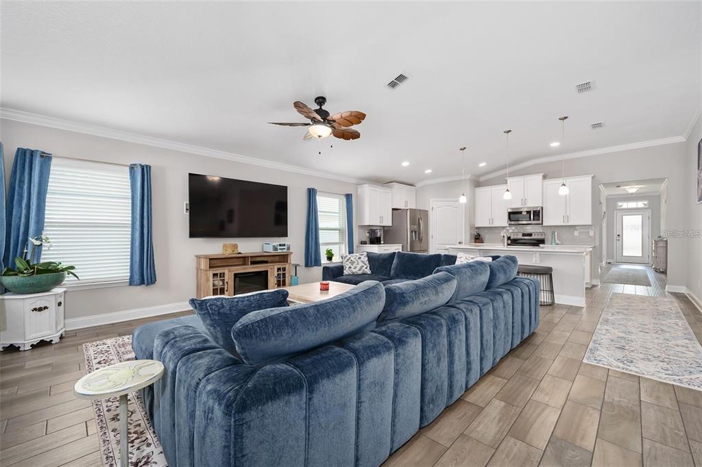 A living room features a blue sectional sofa, a television, and an open-concept kitchen — 64 COASTAL HAMMOCK WAY, ST AUGUSTINE, FL