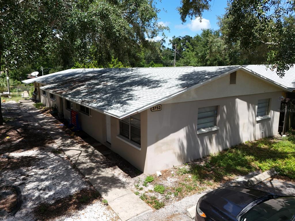 An exterior view of a single-story building with a light-colored facade and a shingled roof — 3753 141ST PLACE, LARGO, FL