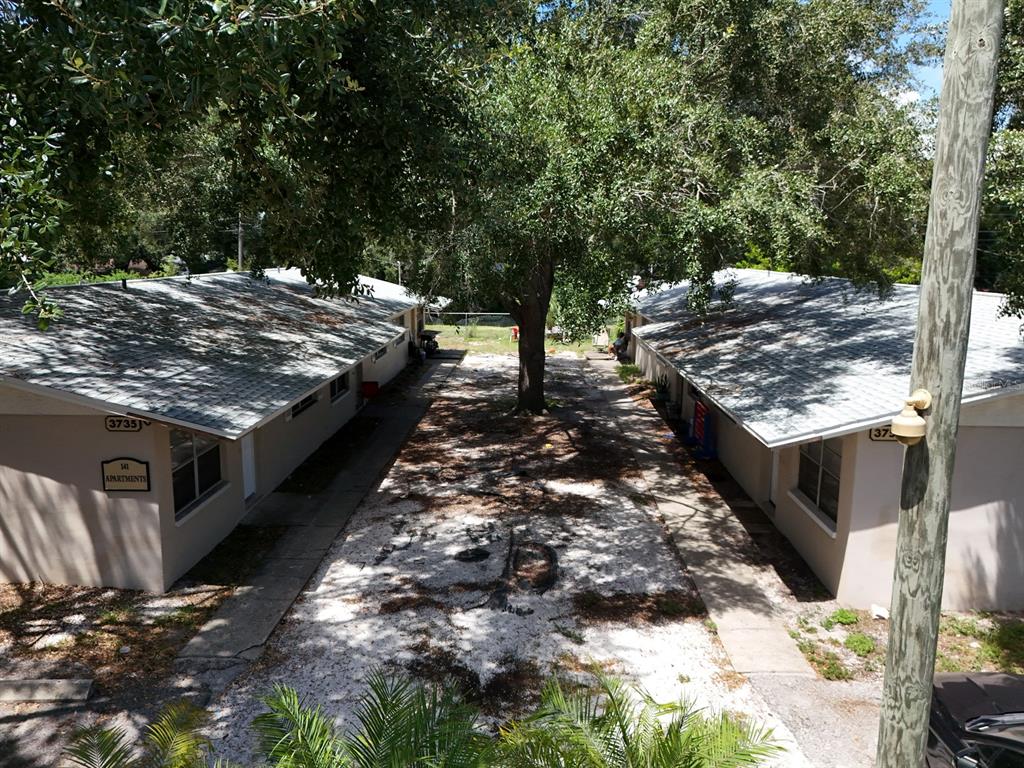 An exterior view of two single-story apartment buildings separated by a tree-lined gravel courtyard — 3753 141ST PLACE, LARGO, FL
