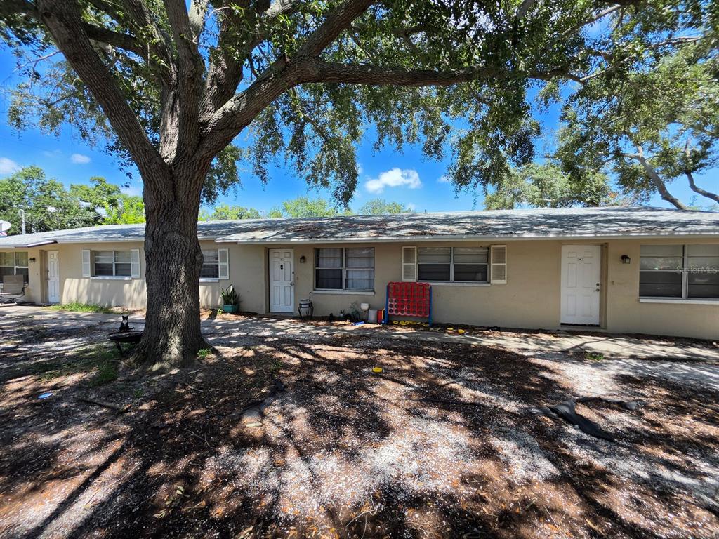 A single-story apartment building exterior features a large tree, tan siding, and white doors — 3753 141ST PLACE, LARGO, FL