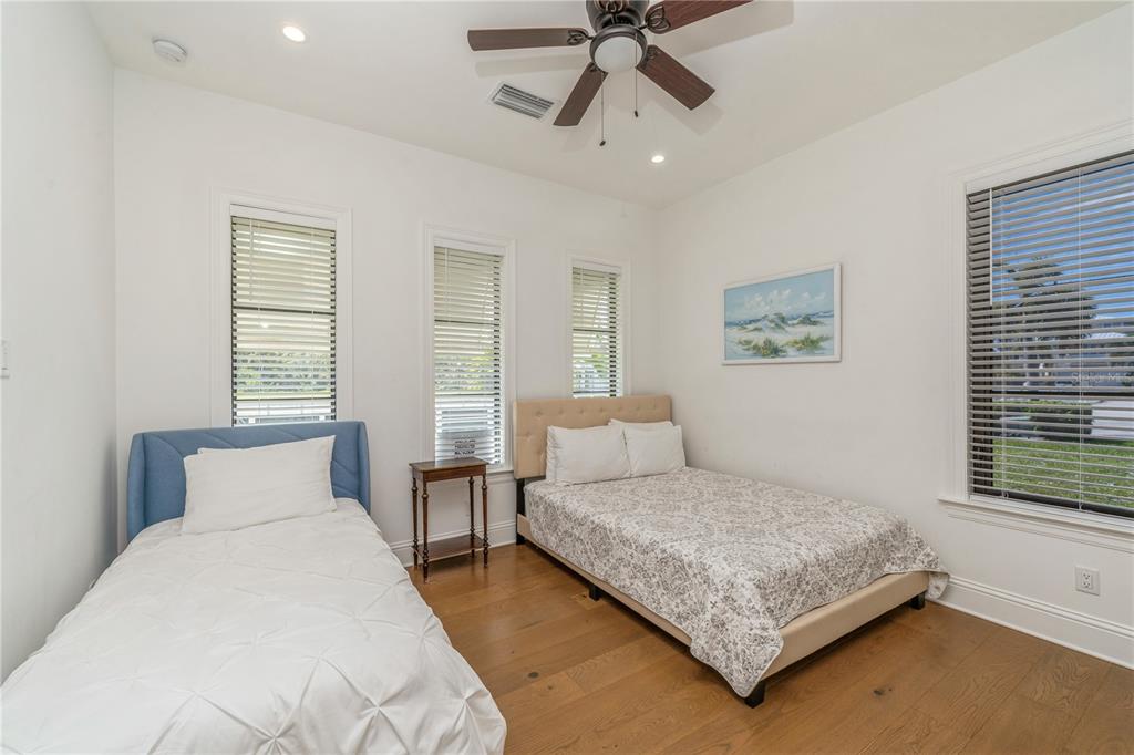 A bedroom features a twin bed, a full bed, wood flooring, and three windows — 132 OCEAN ESTATES DRIVE, HUTCHINSON ISLAND, FL
