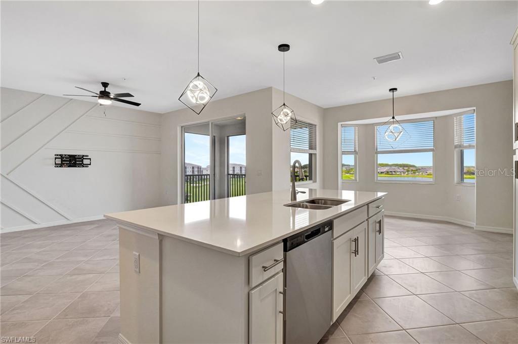 A kitchen island with a stainless steel dishwasher sits before a dining area and patio — 5629 DOUBLE EAGLE CIRCLE UNIT 4242, AVE MARIA, FL