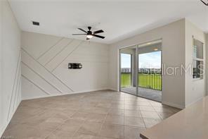 A living room features tile flooring, a ceiling fan, and a decorative accent wall — 5629 DOUBLE EAGLE CIRCLE UNIT 4242, AVE MARIA, FL
