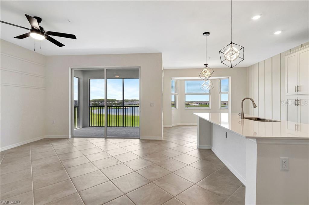 An open-concept kitchen and living area features tile flooring, a kitchen island, and sliding doors — 5629 DOUBLE EAGLE CIRCLE UNIT 4242, AVE MARIA, FL