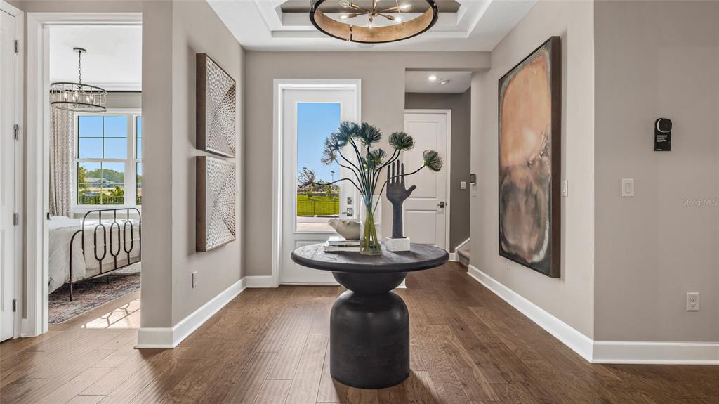 A foyer features a round pedestal table, a glass door, and hardwood flooring — 533 HAMMOCK OAKS BOULEVARD, LADY LAKE, FL