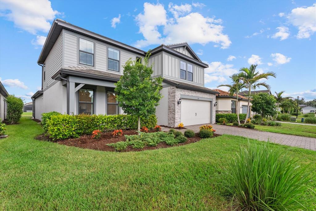 A two-story house with gray siding, stone accents, a two-car garage, and landscaped front yard — 725 GADWALL COURT, BRADENTON, FL