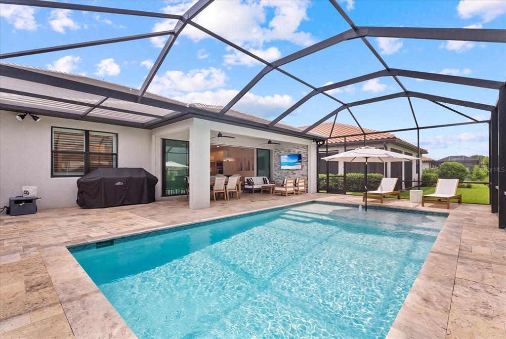 A screened-in patio features a swimming pool, lounge chairs, and an outdoor dining area — 725 GADWALL COURT, BRADENTON, FL