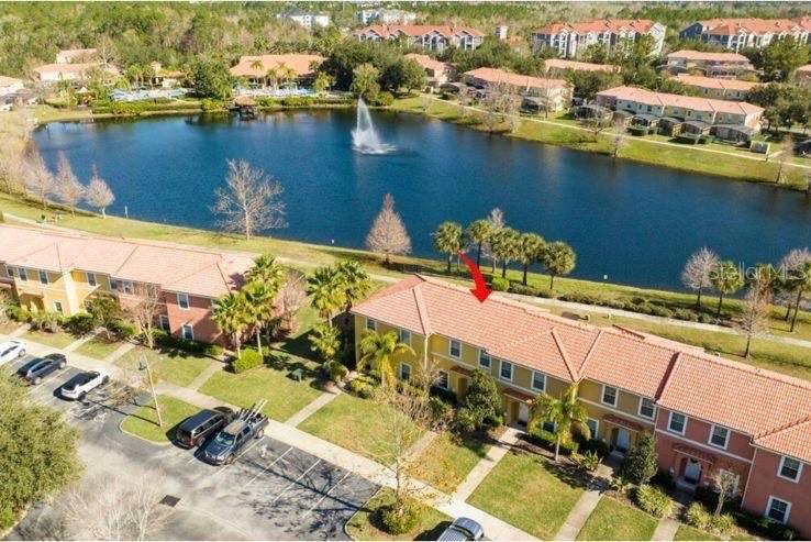 An aerial view shows a multi-story residential building with a red tile roof near a lake — 3065 YELLOW LANTANA LANE, KISSIMMEE, FL