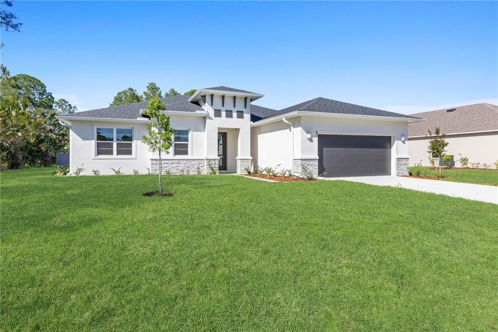 A single-story house with white stucco, stone accents, a dark roof, and a two-car garage — 3162 FERGUS STREET, NORTH PORT, FL