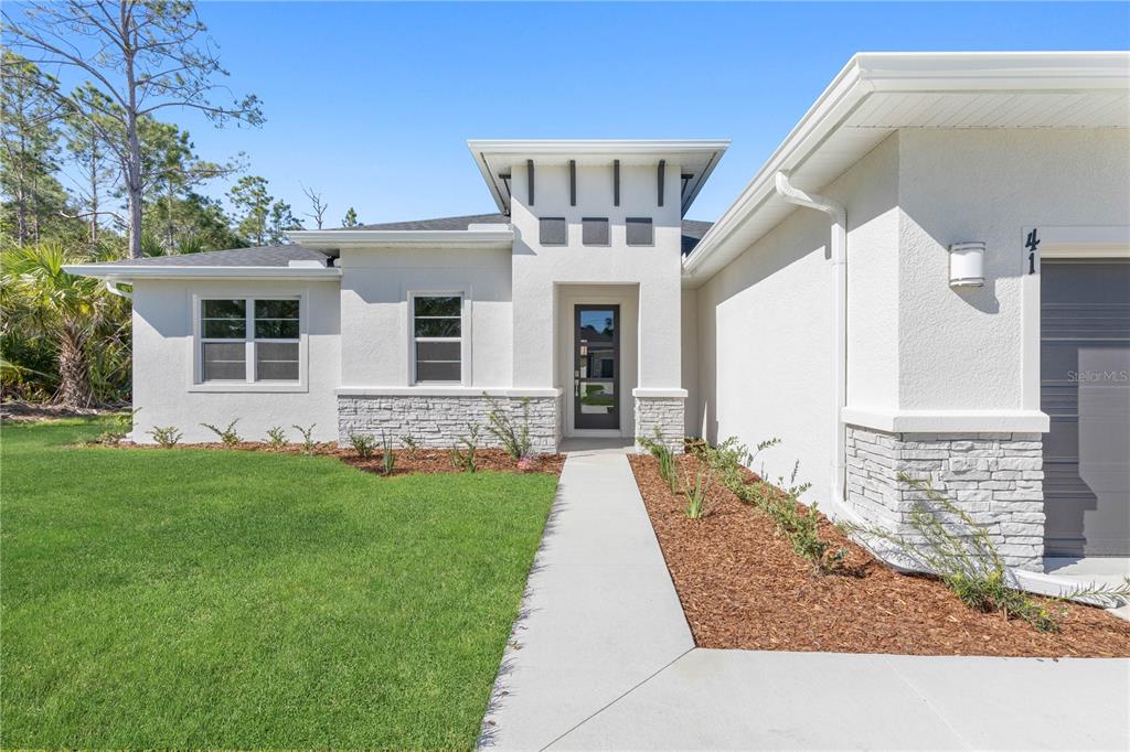 A modern white stucco house features a stone-accented entryway, a glass-paneled door, and a walkway — 3162 FERGUS STREET, NORTH PORT, FL