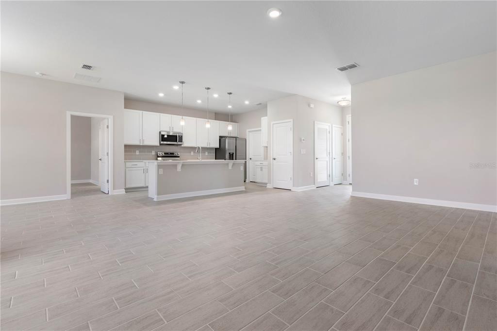 An open-concept kitchen and living area featuring white cabinetry, a breakfast bar, and tile flooring — 3162 FERGUS STREET, NORTH PORT, FL