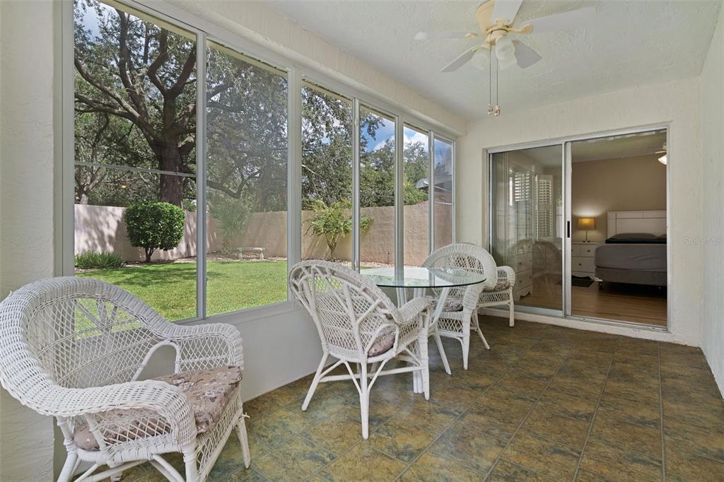 A sunroom with tile flooring, wicker furniture, and large windows overlooking a grassy backyard — 1023 AVALON AVENUE, THE VILLAGES, FL
