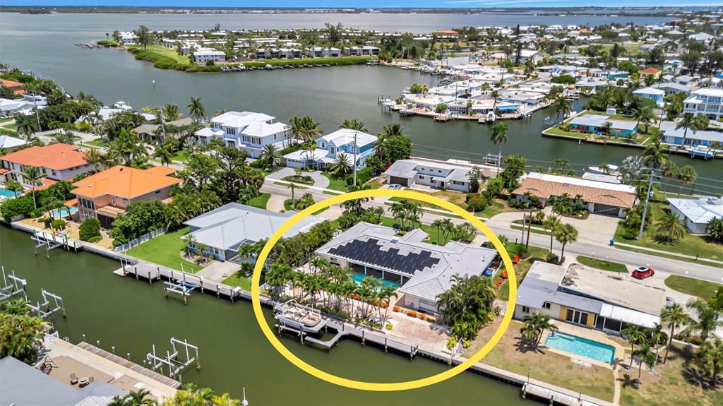 An aerial view shows a waterfront house with a solar-paneled roof and a private dock — 514 KEY ROYALE DRIVE, HOLMES BEACH, FL