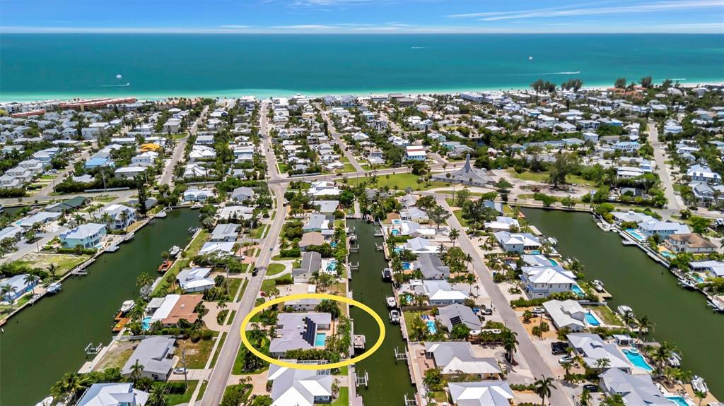 An aerial view shows a waterfront house with a pool along a canal near the beach — 514 KEY ROYALE DRIVE, HOLMES BEACH, FL