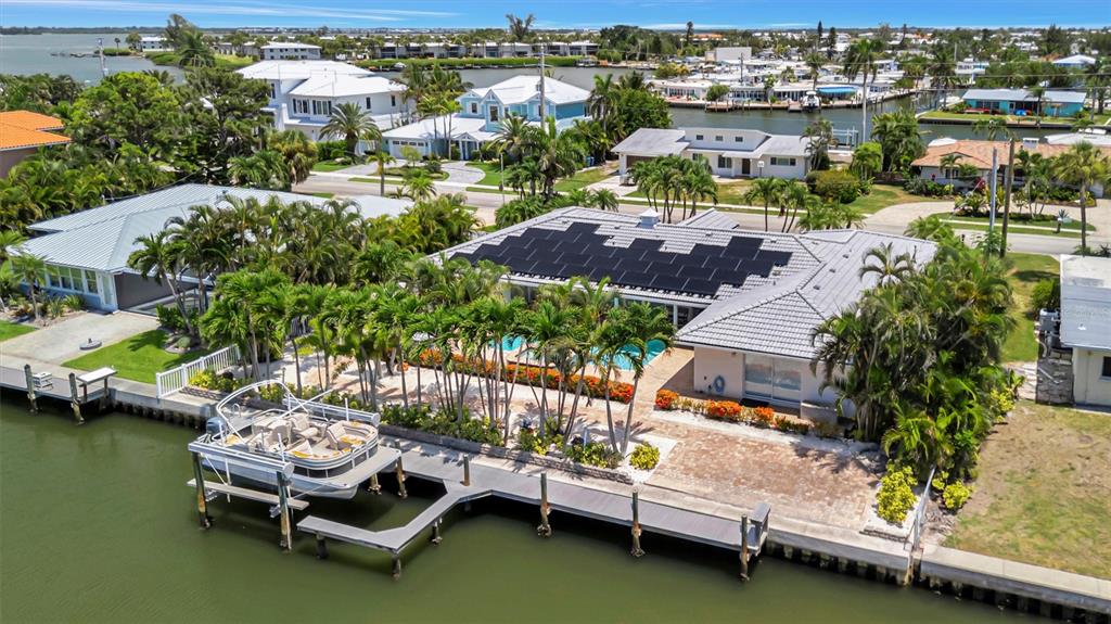 An aerial view shows a waterfront house with solar panels, a pool, and a boat dock — 514 KEY ROYALE DRIVE, HOLMES BEACH, FL