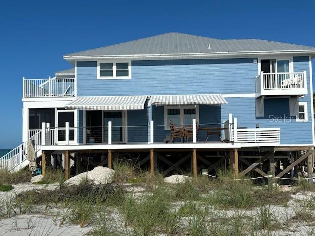 A blue two-story house on stilts sits on a sandy beach with a wooden deck — 221 N GULF BOULEVARD UNIT A, PLACIDA, FL