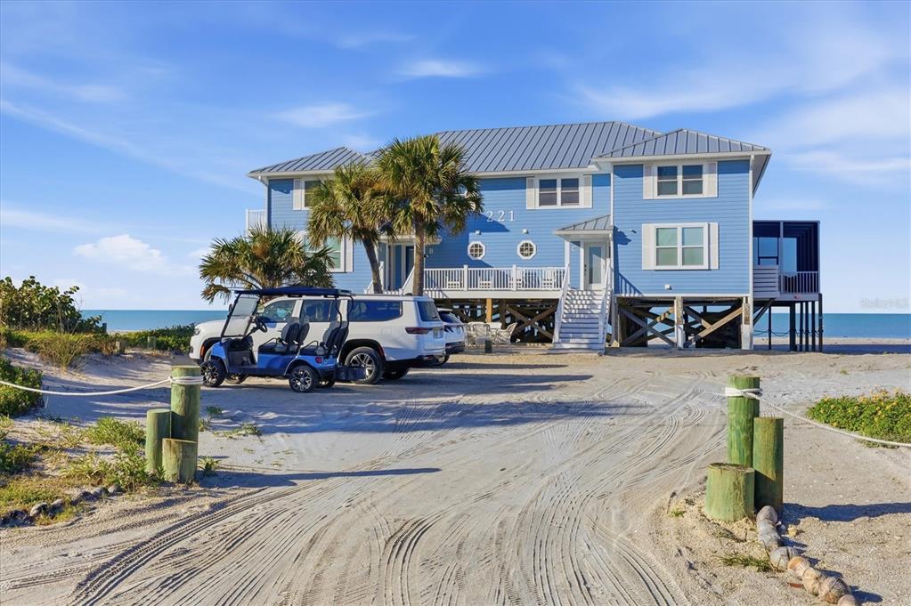 A blue two-story beach house stands on stilts with a golf cart parked in front — 221 N GULF BOULEVARD UNIT A, PLACIDA, FL