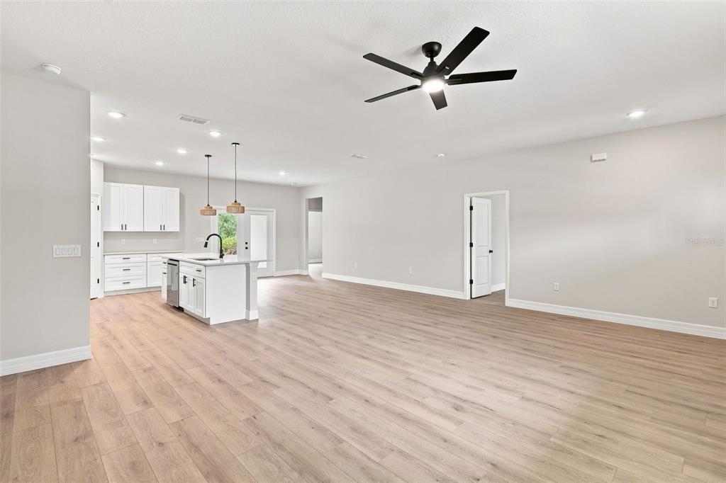 An open-concept kitchen and living area featuring light wood flooring, white cabinetry, and a ceiling fan — 41325 ROYAL TRAILS ROAD, EUSTIS, FL