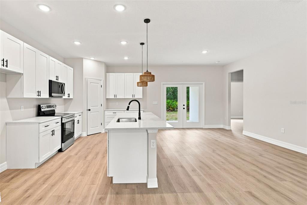 A modern kitchen with white cabinets, a central island, and light wood-look flooring — 41325 ROYAL TRAILS ROAD, EUSTIS, FL