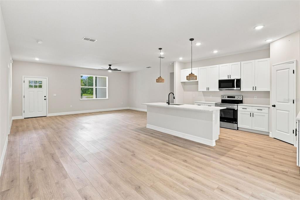 An open-concept kitchen and living area featuring white cabinets, a central island, and light flooring — 41325 ROYAL TRAILS ROAD, EUSTIS, FL