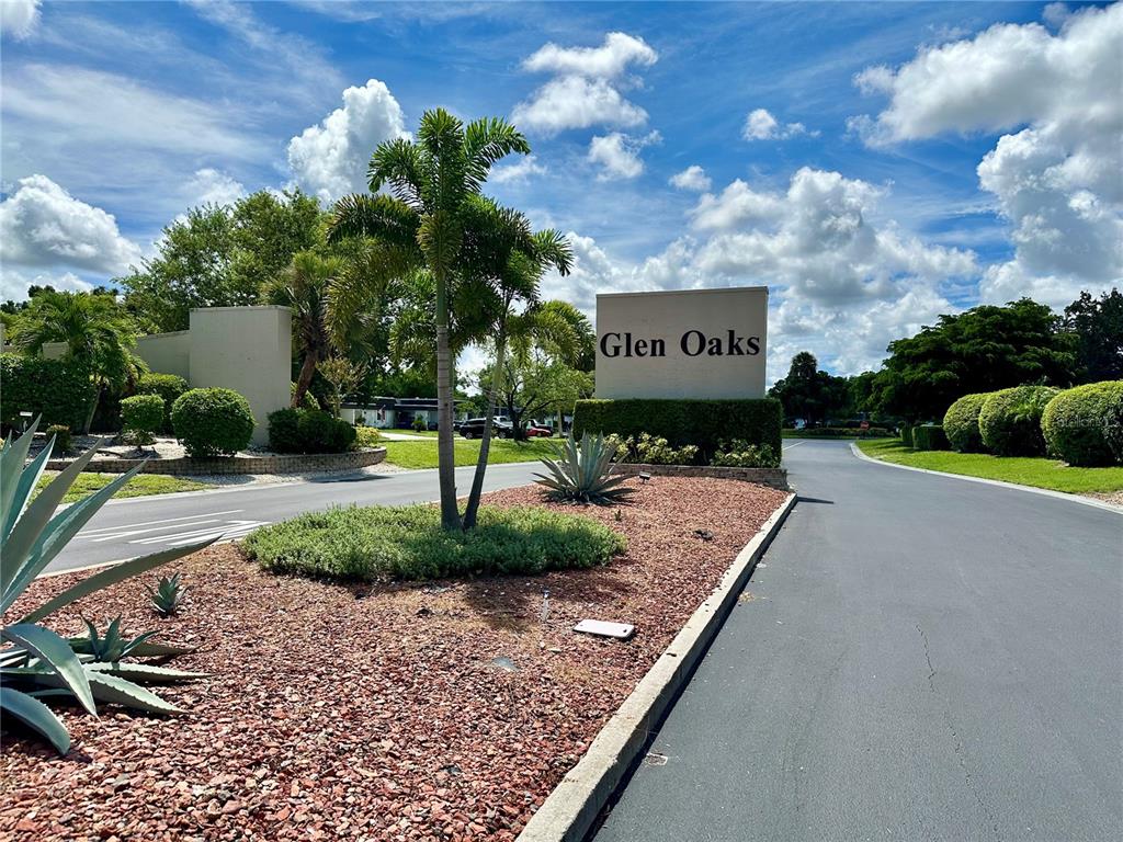 A sign for Glen Oaks stands at the entrance to a paved residential road — 1330 GLEN OAKS DRIVE E UNIT 370D, SARASOTA, FL