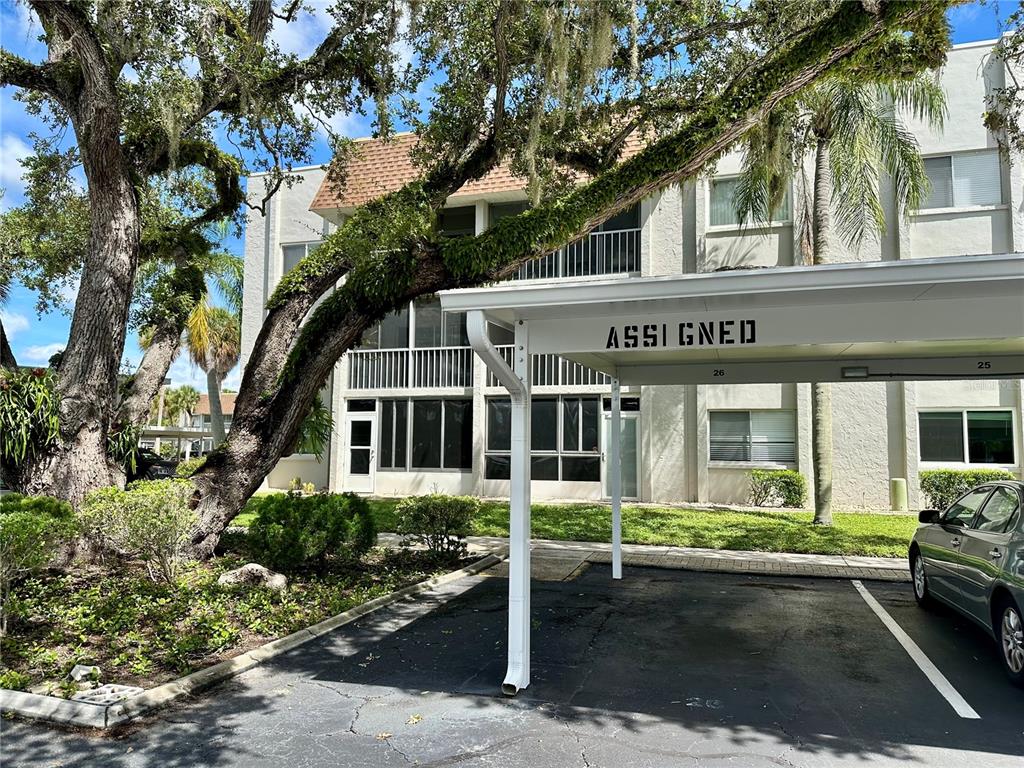 A multi-story apartment building features a covered parking space and large mossy oak trees — 1330 GLEN OAKS DRIVE E UNIT 370D, SARASOTA, FL
