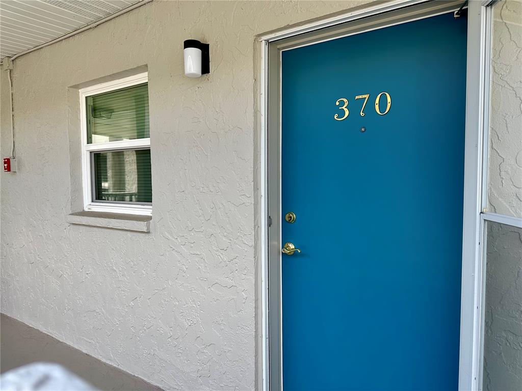 A teal front door with the number 370 is set into a textured beige exterior wall — 1330 GLEN OAKS DRIVE E UNIT 370D, SARASOTA, FL