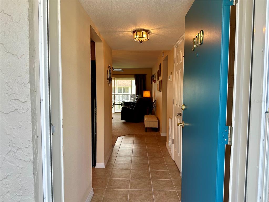A view from an open teal door into a tiled entryway leading to a living area — 1330 GLEN OAKS DRIVE E UNIT 370D, SARASOTA, FL