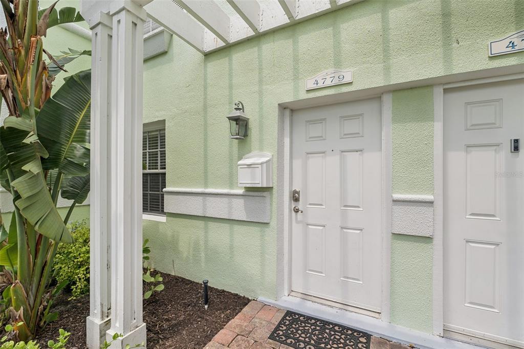 A two-story lime green townhouse exterior with palm trees and a paved parking lot — 4779 COQUINA KEY DRIVE SE, ST PETERSBURG, FL