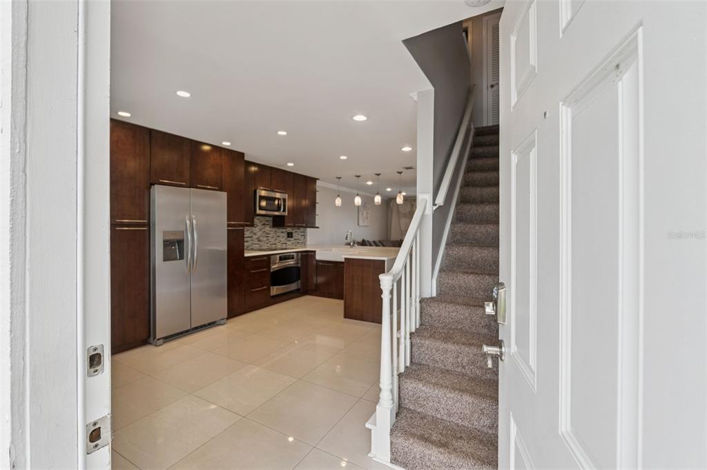 An entryway with light gray walls, tile flooring, a staircase, and a white front door — 4779 COQUINA KEY DRIVE SE, ST PETERSBURG, FL