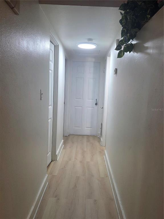 A long room with white block walls, wood-look flooring, and two windows with curtains — 1005 KIMBALL DRIVE, OCOEE, FL
