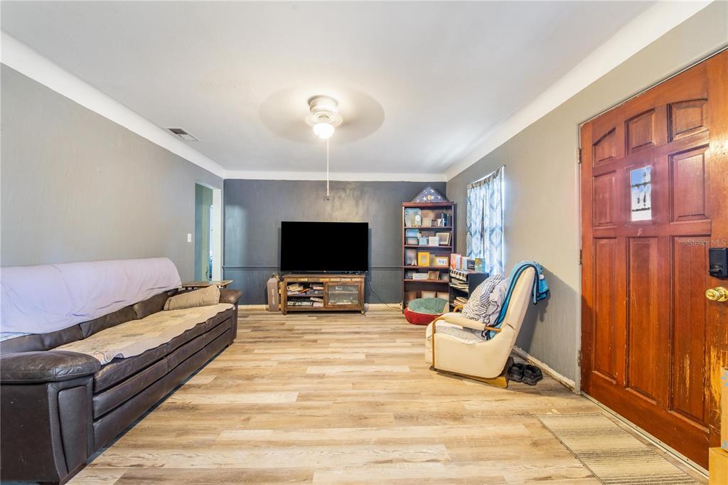 A living room features wood-look flooring, gray walls, a ceiling fan, and a wooden front door — 400 E POMELO STREET, LAKE ALFRED, FL